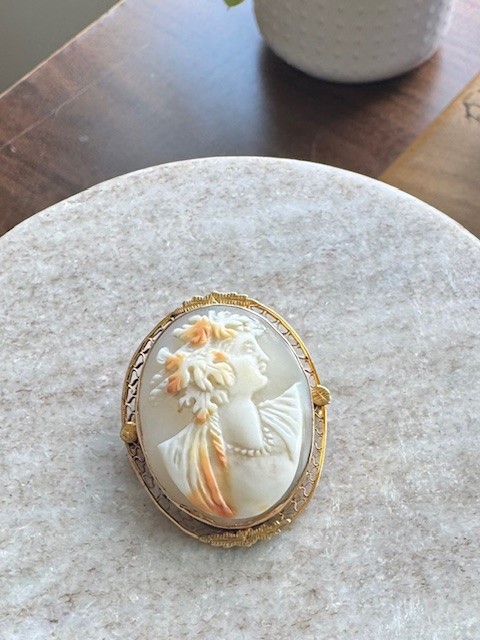 10K yellow gold shell cameo brooch/pendant, hand-carved right-facing female bust with floral hair and pearl necklace detail, polychrome shell, open-work filigree oval frame with foliate appliqués, loop bail and pin back, Edwardian circa 1900