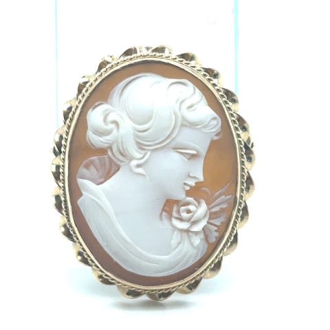 14K yellow gold shell cameo brooch/pendant, hand-carved right-facing female bust with upswept curled hair and rose shoulder detail, natural cream and peach shell coloration, rope-twist inner border and scalloped outer frame, hidden flip-up bail and pin back, 1¾" x 1⅛", 3.5 grams, 1970s