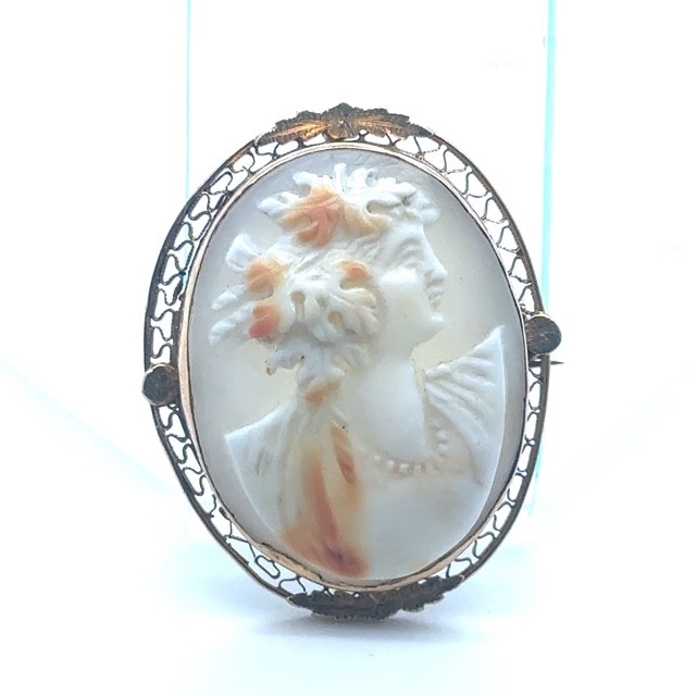 10K yellow gold shell cameo brooch/pendant, hand-carved right-facing female bust with floral hair and pearl necklace detail, polychrome shell, open-work filigree oval frame with foliate appliqués, loop bail and pin back, Edwardian circa 1900