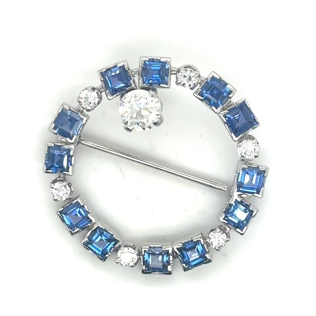 Platinum old European cut diamond and square-cut blue sapphire circle brooch, approx. 0.83 ct OEC featured diamond at crown, 0.54 CTW OEC accent diamonds, square sapphires in alternating collet settings, straight pin bar, Art Deco